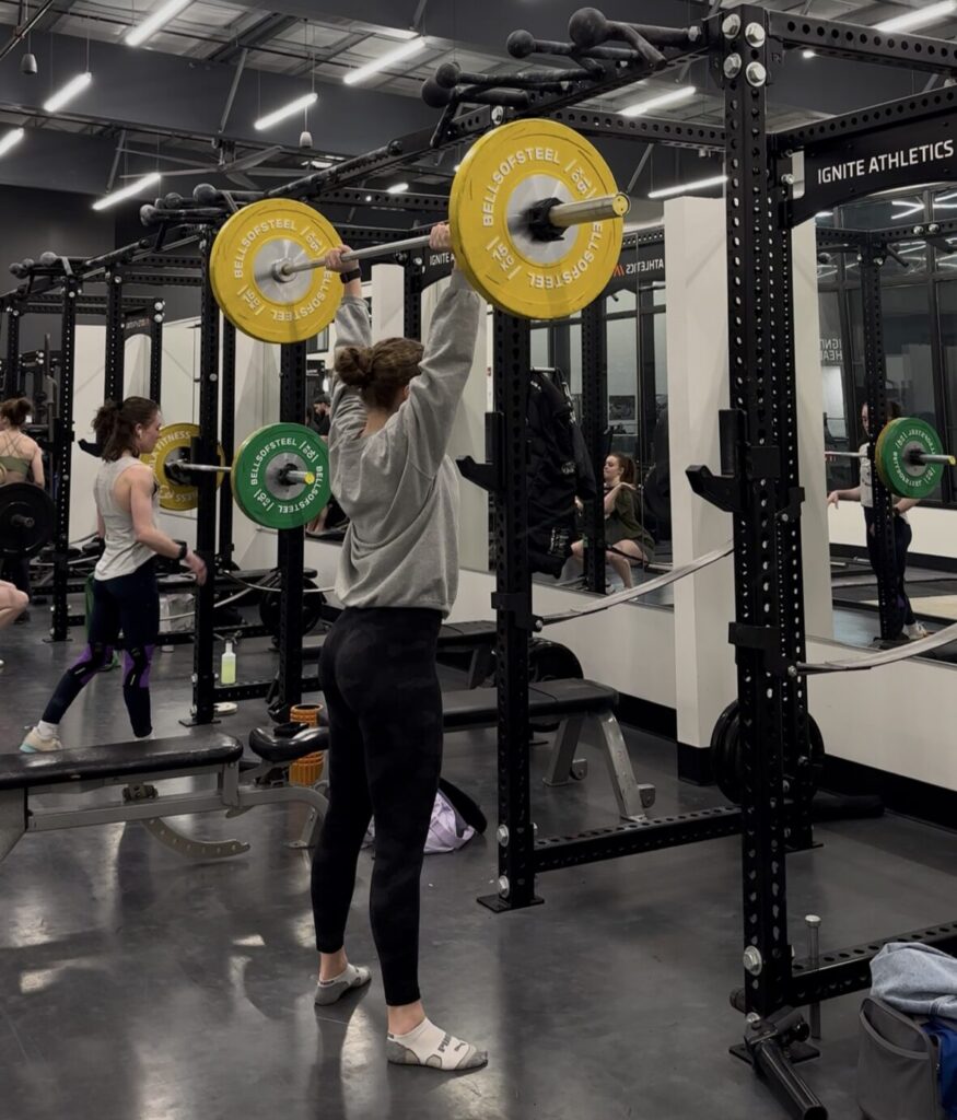 Female athlete lifting weights in a gym.